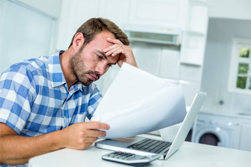 Worried man looking at a document in front of a laptop