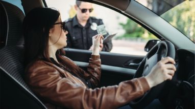 Woman inside her car giving her drivers license to a police officer