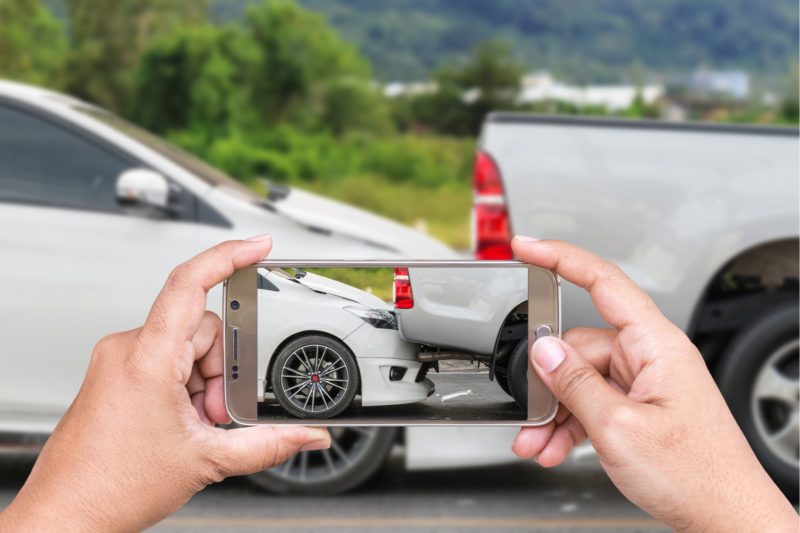 Hands taking a picture of a car accident with a smartphone