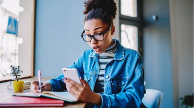 Woman looking for car insurance on her phone and taking notes