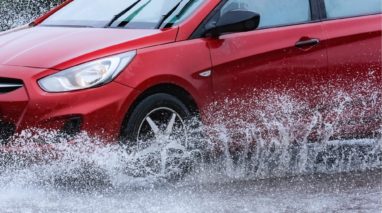 Red car driving safely in the rain