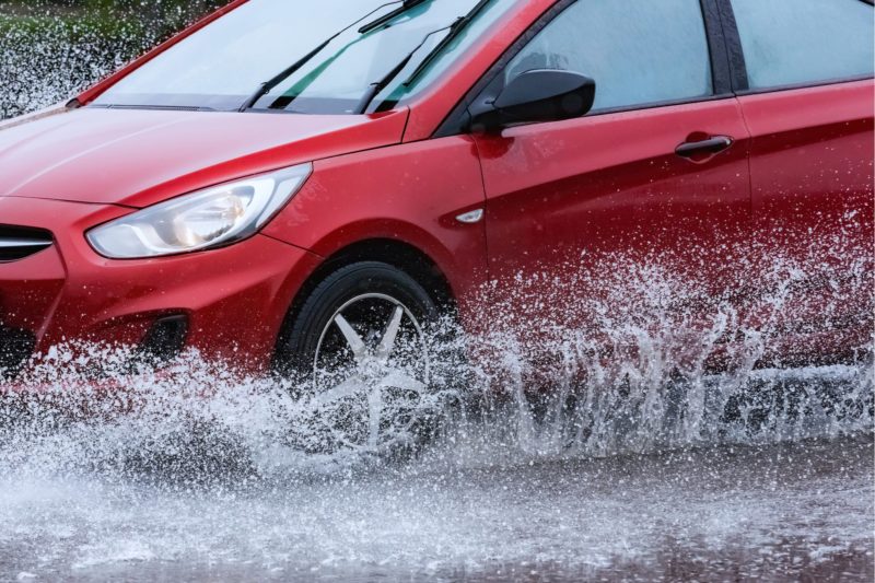 Red car driving safely in the rain