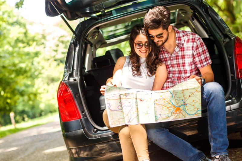 Happy couple looking at a map in the back of their car