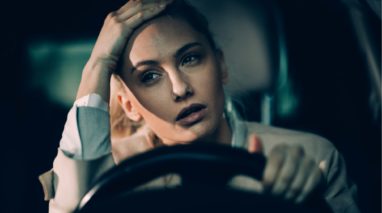 Frustated woman sitting in car with a hand on her head because she needs and SR22