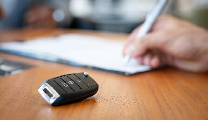 close up of car keys with hand writing on paper on the background