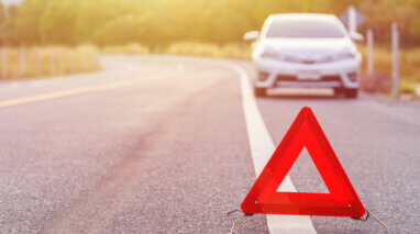 red emergency sign on the highway with a car on the background