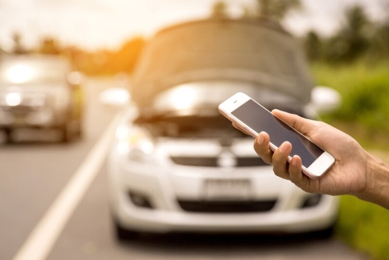 Using a mobile phone call a car mechanic because car was broken