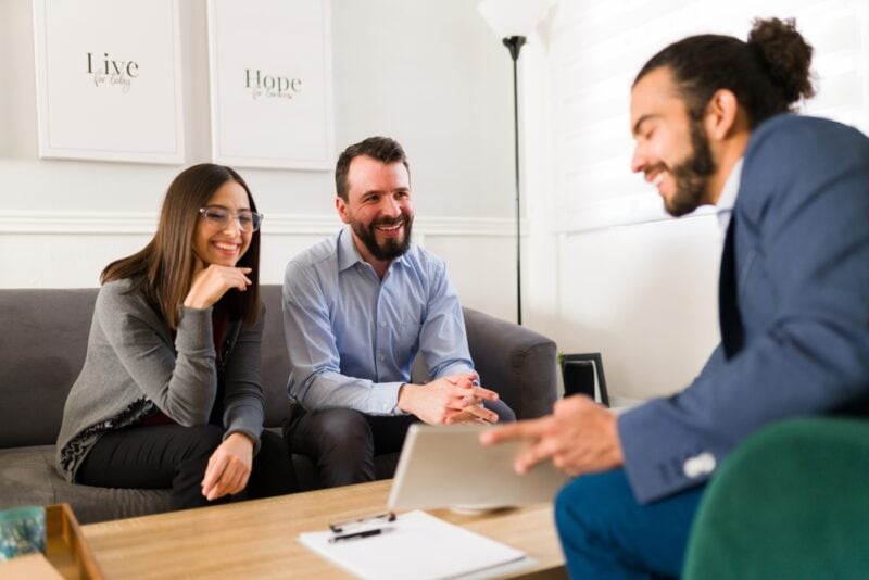 Young male insurance agent with smiling couple