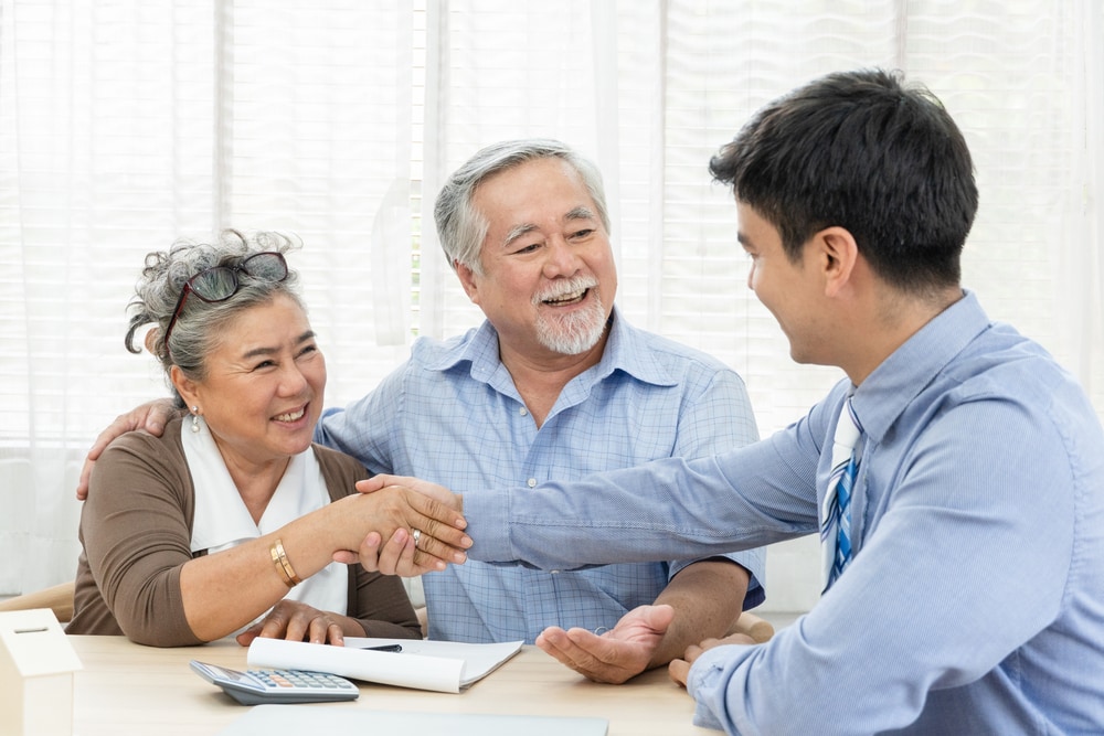 Young insurance agent with happy older Asian couple customers