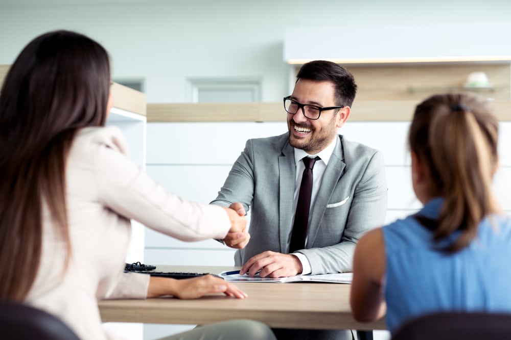 Insurance agent smiling and shaking hands with customer