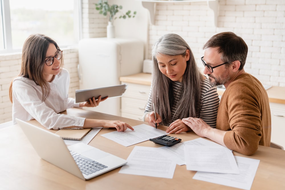 Smiling insurance agent helps young couple navigate through insurance bill