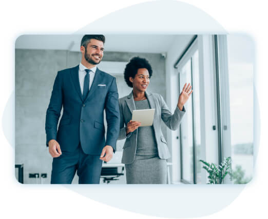 Man and woman business people next to window, woman with hand raised.